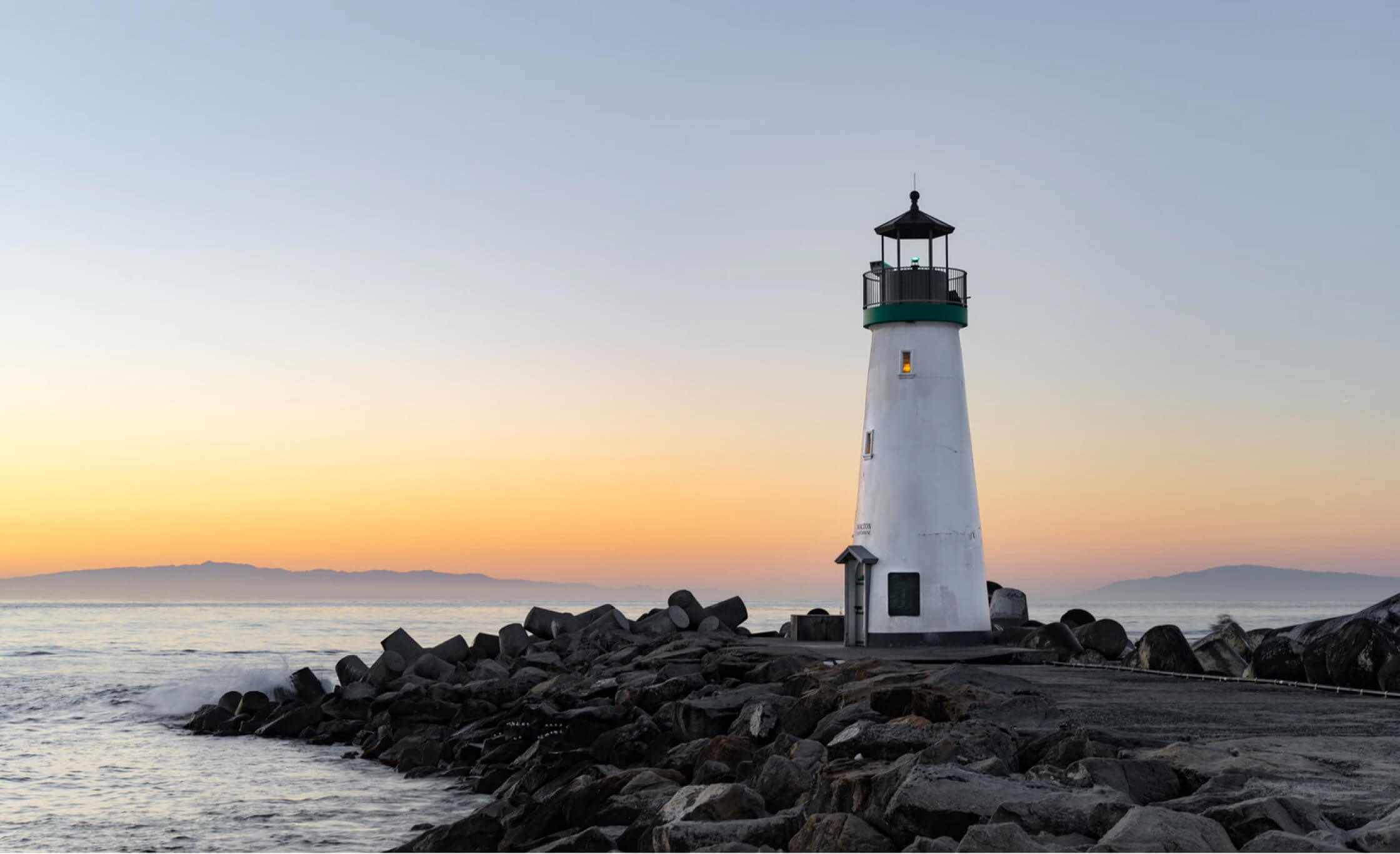 A lighthouse stands above a shallow cliff.